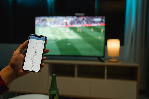 Close-up shot of football fan checking the match schedule on his smartphone