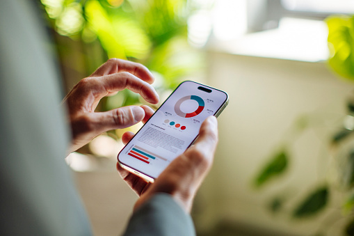 A person holding a smartphone displaying a data analysis application